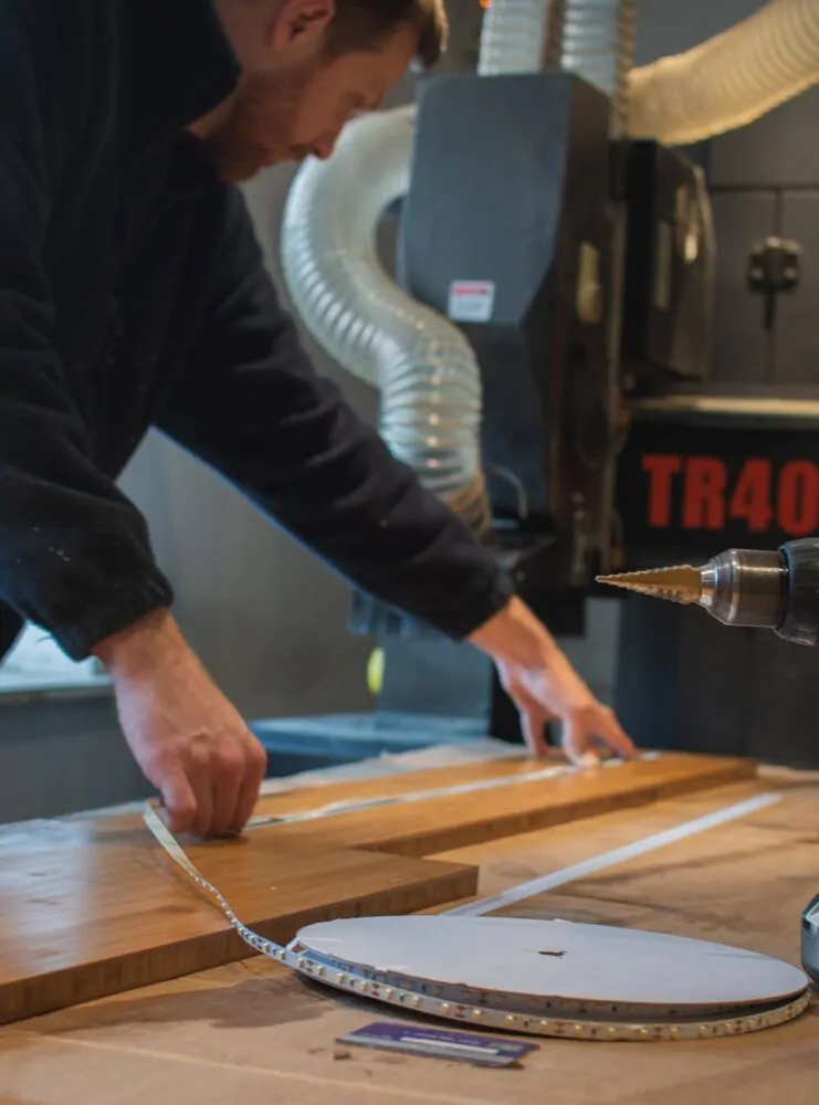 A skilled craftsman measuring and preparing a wooden panel for a bespoke campervan interior