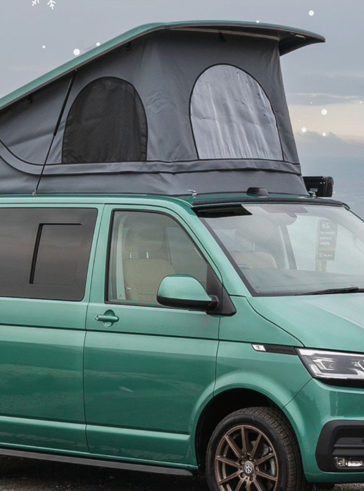 Green camper against a backdrop of the downs with superimposed snow